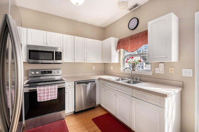 kitchen featuring visible vents, light countertops, stainless steel appliances, white cabinetry, and a sink