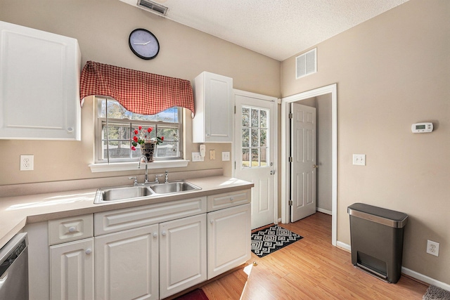 kitchen featuring visible vents, dishwasher, white cabinetry, and a sink