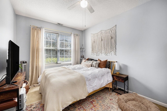 carpeted bedroom featuring visible vents, baseboards, a textured ceiling, and a ceiling fan