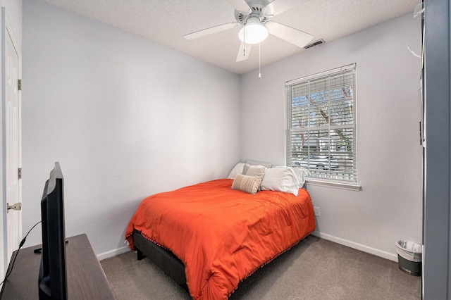 carpeted bedroom featuring visible vents, baseboards, a textured ceiling, and a ceiling fan