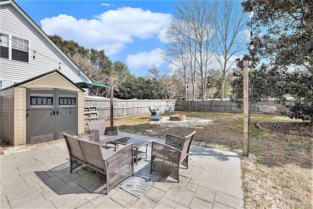 view of patio / terrace with a fenced backyard, an outbuilding, a fire pit, and a storage shed