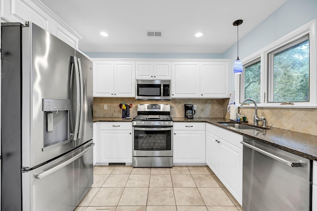 kitchen with tasteful backsplash, appliances with stainless steel finishes, sink, and white cabinets