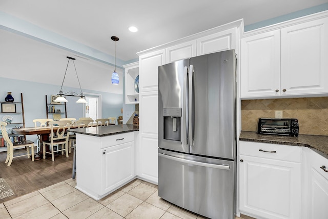 kitchen featuring white cabinetry, kitchen peninsula, pendant lighting, and stainless steel fridge