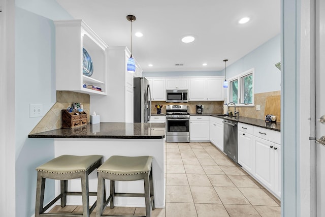 kitchen featuring stainless steel appliances, sink, kitchen peninsula, decorative light fixtures, and white cabinets