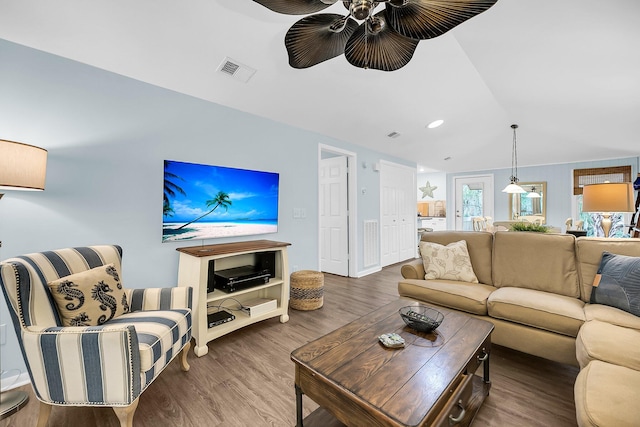 living room with hardwood / wood-style flooring, ceiling fan, and vaulted ceiling