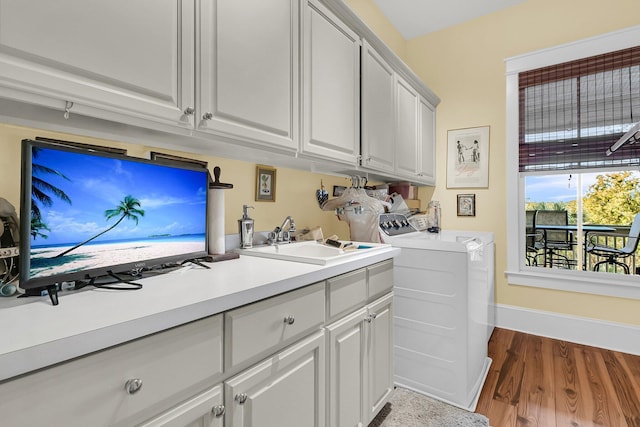 laundry room with hardwood / wood-style flooring, cabinets, sink, and washer and dryer