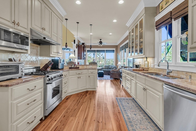 kitchen with light wood-type flooring, ornamental molding, appliances with stainless steel finishes, pendant lighting, and white cabinets