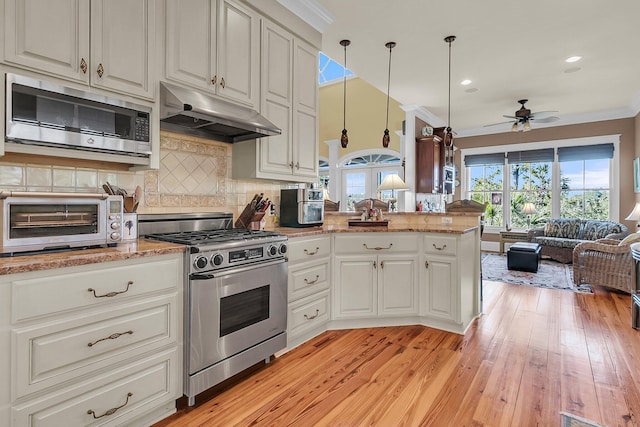 kitchen with decorative light fixtures, white cabinets, backsplash, kitchen peninsula, and stainless steel appliances