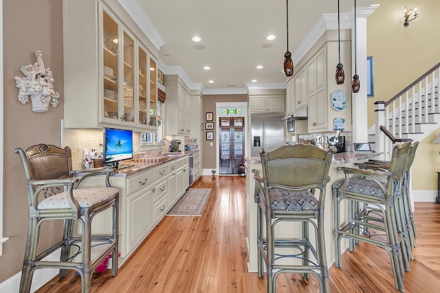 kitchen with a breakfast bar, tasteful backsplash, hanging light fixtures, appliances with stainless steel finishes, and white cabinets