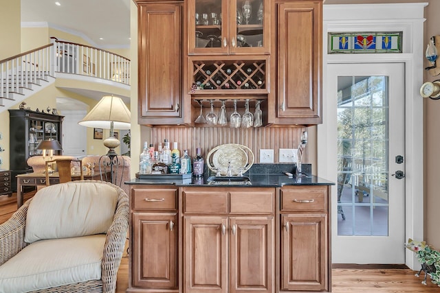 bar with tasteful backsplash, crown molding, and light hardwood / wood-style flooring