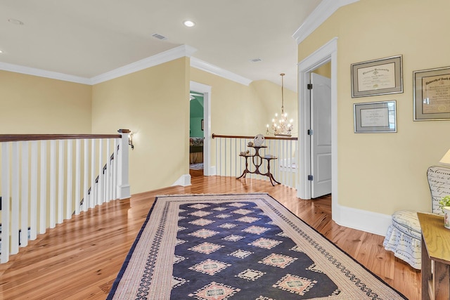 hall with a notable chandelier, wood-type flooring, and ornamental molding