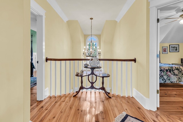 corridor with an inviting chandelier, crown molding, and light wood-type flooring