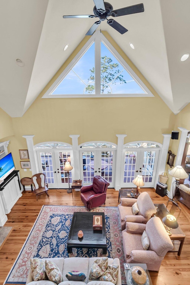 living room with hardwood / wood-style flooring, high vaulted ceiling, and french doors