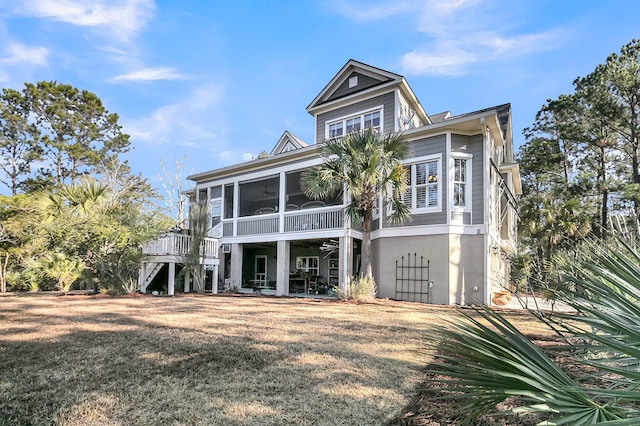 rear view of house with ceiling fan, a yard, and a sunroom