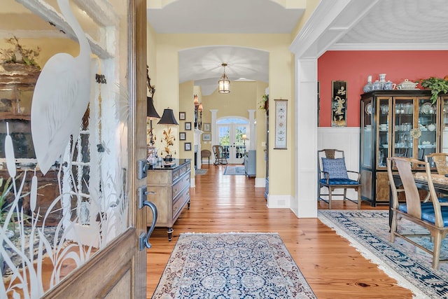 entrance foyer with ornamental molding, light hardwood / wood-style floors, and french doors