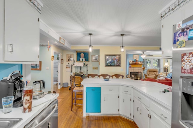 kitchen with decorative light fixtures, light hardwood / wood-style flooring, appliances with stainless steel finishes, ceiling fan, and white cabinets