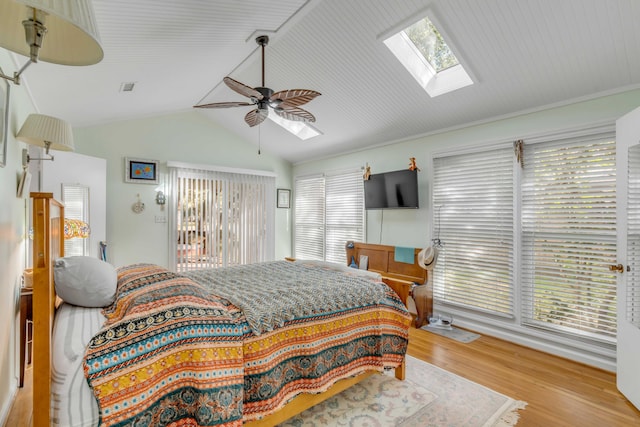 bedroom with lofted ceiling with skylight, access to outside, hardwood / wood-style floors, and ceiling fan