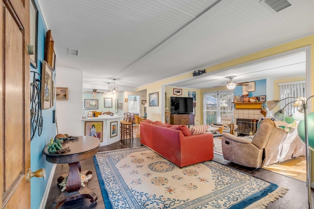 living room with a tiled fireplace, hardwood / wood-style flooring, and ceiling fan