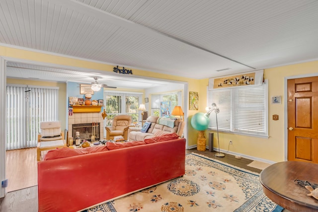 living room featuring hardwood / wood-style flooring, a tile fireplace, ceiling fan, and crown molding