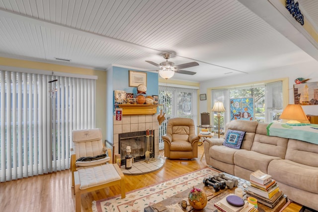 living room featuring crown molding, ceiling fan, a fireplace, and hardwood / wood-style floors