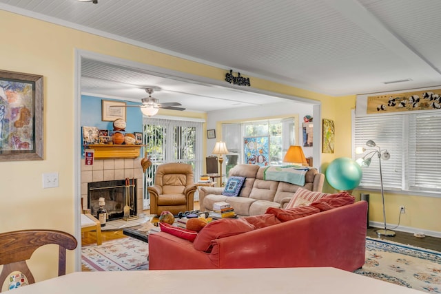 living room featuring a tiled fireplace, hardwood / wood-style floors, and crown molding