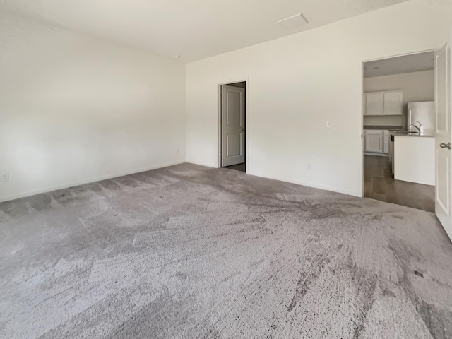 unfurnished room with a sink and dark carpet