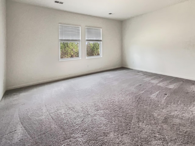 carpeted spare room with visible vents and baseboards