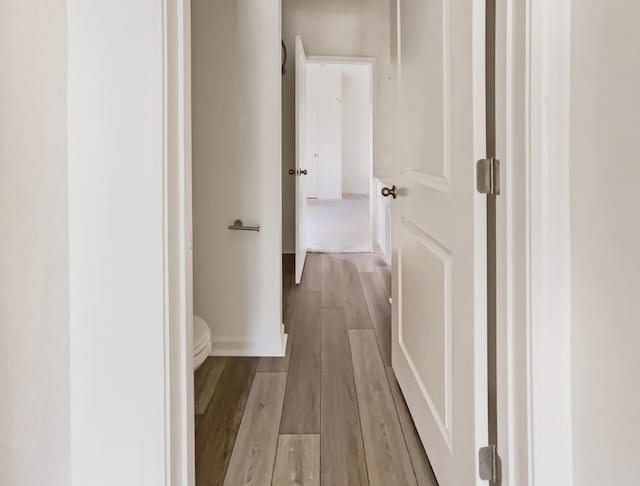 hallway featuring wood finished floors and baseboards