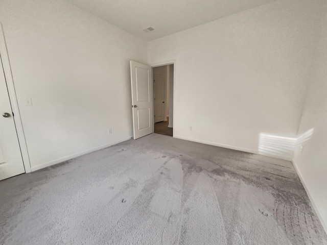 carpeted empty room featuring baseboards and visible vents