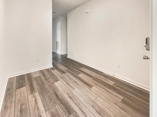 spare room featuring baseboards and dark wood-type flooring