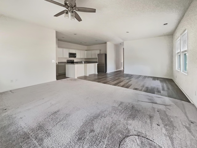 unfurnished living room with wood finished floors and a ceiling fan