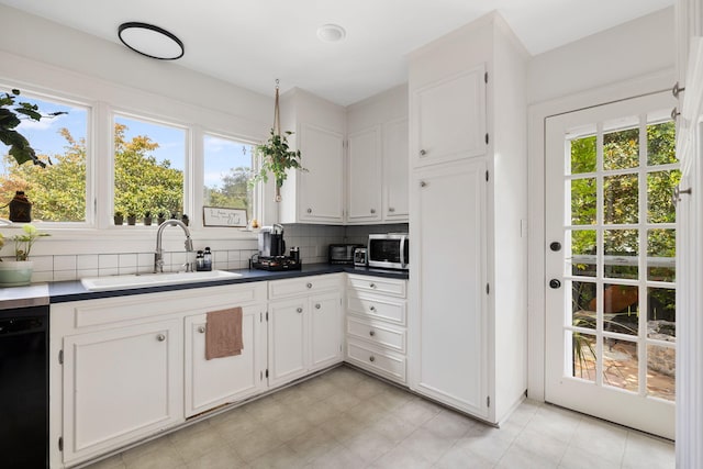 kitchen with backsplash, white cabinets, dishwasher, and sink