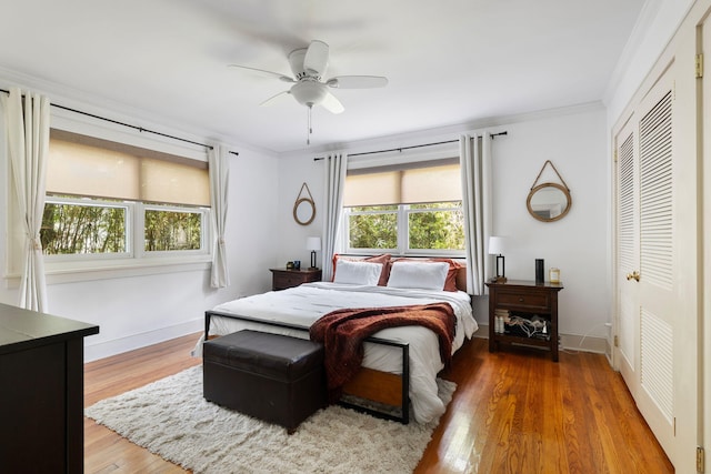 bedroom with ornamental molding, hardwood / wood-style floors, ceiling fan, and a closet