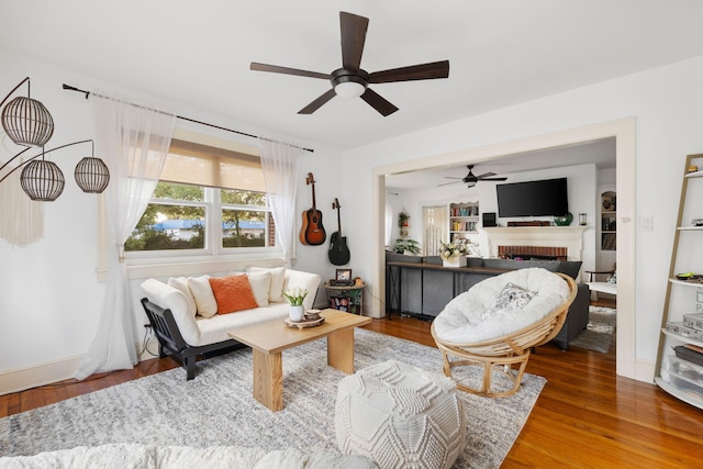 living room with ceiling fan, hardwood / wood-style flooring, and a fireplace