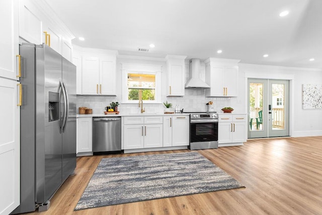 kitchen featuring white cabinets, appliances with stainless steel finishes, decorative backsplash, and custom range hood