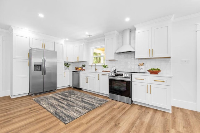 kitchen with appliances with stainless steel finishes, premium range hood, white cabinetry, and light hardwood / wood-style flooring