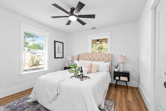 bedroom with multiple windows, ceiling fan, and hardwood / wood-style flooring