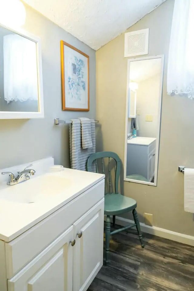 bathroom featuring visible vents, lofted ceiling, wood finished floors, baseboards, and vanity