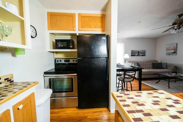 kitchen featuring black appliances, a textured ceiling, open floor plan, light wood-style floors, and ceiling fan