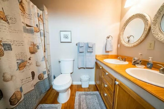 full bathroom featuring double vanity, toilet, wood finished floors, and a sink