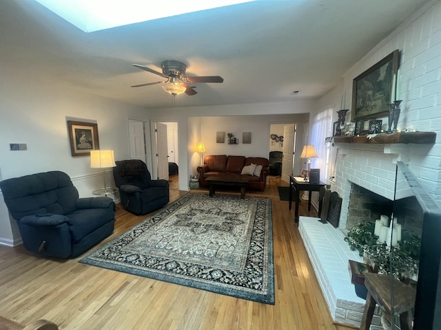 living area with a ceiling fan, wood finished floors, and a fireplace