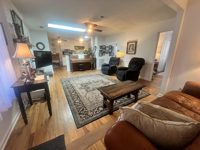 living area with visible vents, ceiling fan, and light wood-style flooring