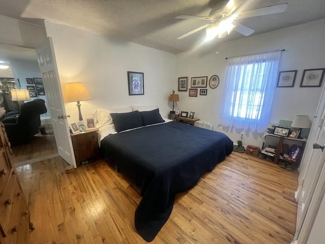 bedroom featuring ceiling fan, light wood-type flooring, and a textured ceiling