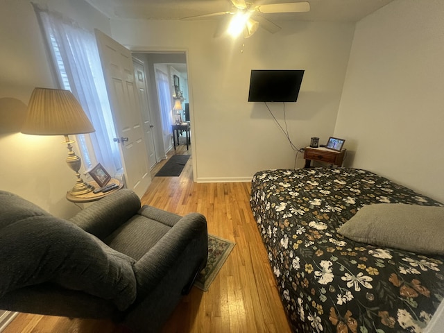 bedroom featuring baseboards, light wood-type flooring, and ceiling fan