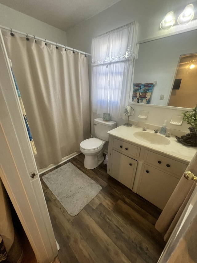 bathroom featuring a shower with shower curtain, toilet, vanity, and wood finished floors