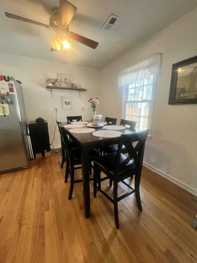 dining space featuring baseboards, visible vents, a ceiling fan, and light wood-style floors