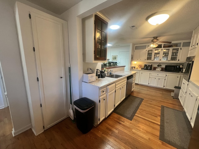 kitchen featuring a sink, white cabinetry, stainless steel appliances, light wood-style floors, and light countertops