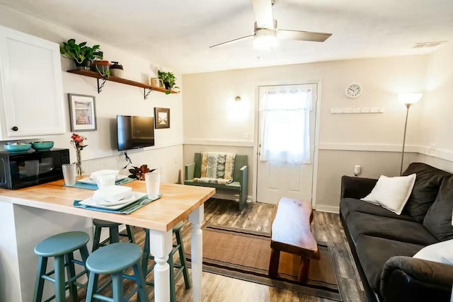 living room featuring ceiling fan, visible vents, and wood finished floors