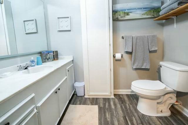 bathroom featuring vanity, toilet, wood finished floors, and baseboards