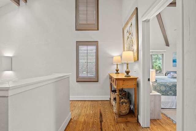 corridor with hardwood / wood-style flooring and lofted ceiling with beams